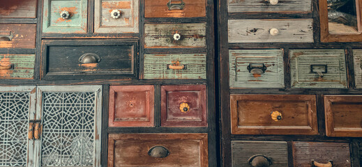Vintage wooden drawers close-up. Old handmade colorful chest of drawers and cabinets background.