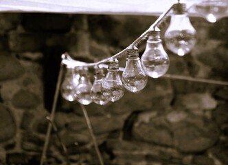 Lampadine appese in fila, sfondo di pietre, luce soffusa.

