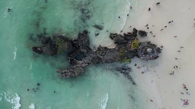 Descending drone video of the Willy's Rock, a popular stone formation located in shallow water on the  western coast of Boracay island, Philippines. Top view.