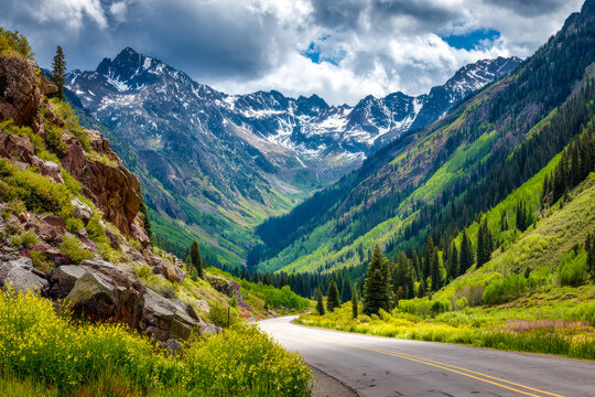 Scenic mountain valley with lush greenery and snow-capped peaks along a winding road