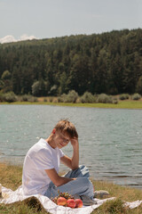 Fototapeta premium Boy in a white T-shirt on the shore of a lake in the mountains. Beautiful landscape. Bulgaria