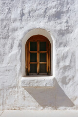Wooden arched window in white textured wall.