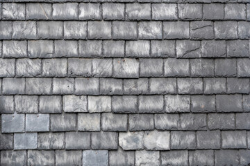Grey slate tiles are laid tightly together to reveal weathered texture,original architectural element,traditional craftsmanship of roofers creating waterproof covering,nine rows of tiles