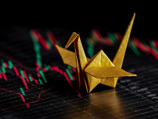 Gold origami crane placed on financial market chart background