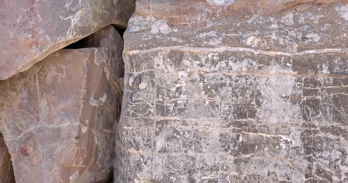 Slider motion closeup of weathered black rocks with uniform steaks of mineral on abstract surface