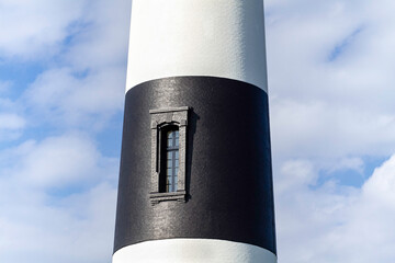 Detail of a Black and White lighthouse against a cloudy blue sky