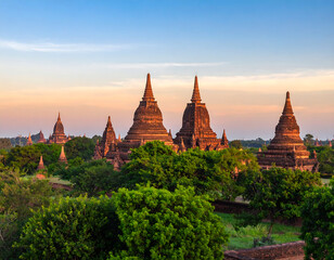 Fototapeta premium Serene Sunset over Ancient Bagan Temples, Myanmar: Picturesque Landscape Photography, Warm Golden Hour Light, Lush Greenery.