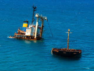 The Manassa Rose shipwreck lies tilted in clear blue waters near Crete, Greece, with a smaller...