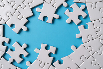 Obraz premium White jigsaw puzzle pieces on blue background strategy teamwork solution concept complete the puzzle game