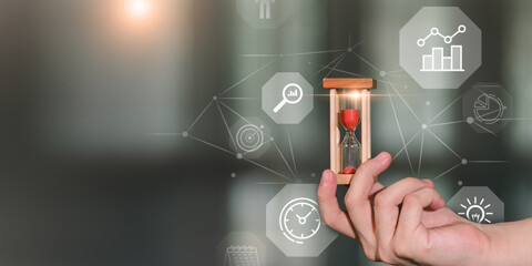 Hand holding hourglass with digital business icons, symbolizing time management, deadline tracking, productivity planning, and efficiency optimization in modern professional environments.