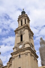 A majestic view of the clock tower of Basilica de Nuestra Señora del Pilar in Zaragoza, Spain, captured under a partly cloudy sky