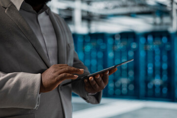 Close up of data center admin using tablet to protect servers from exploitable software vulnerabilities, auditing systems. Cybersecurity specialist using notebook looking for bugs slowing down servers