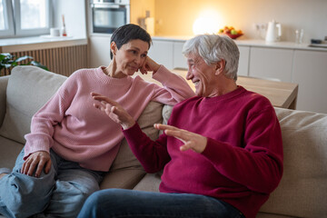 Fototapeta premium Senior husband enthusiastically shares memories, wife attentively listen. Elderly couple bonding storytelling, marital communication, joyful retirement, laughing spouses at home, family foundation