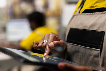 Close up of female employee ensuring awb tracking info within e-commerce inventory system on tablet, overseeing storage distribution protocols. Logistics planning for smooth cargo movement.