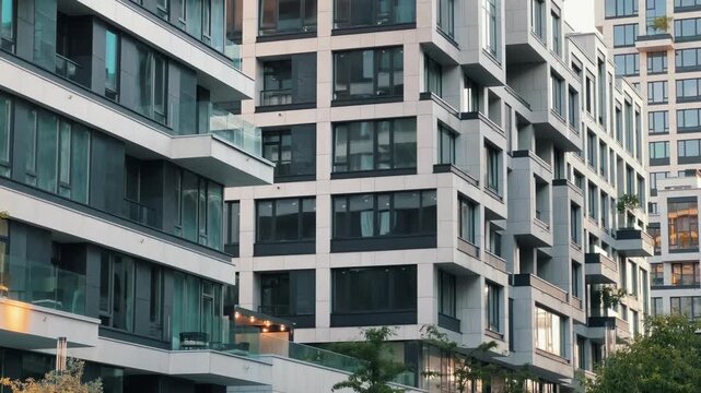 Modern residential complex long angle view showing multiple luxury apartment buildings along street with contemporary architecture and evening lighting