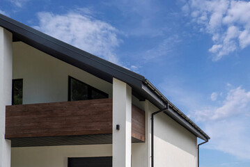 Modern house facade with wooden balcony and metal roof
