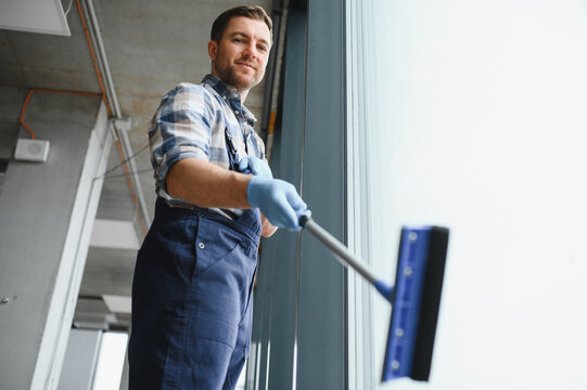 Professional cleaning service worker washing windows in modern office building