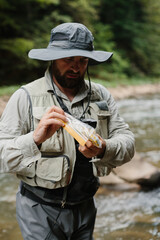 Fototapeta premium Fisherman choosing bait for trout fishing in river