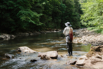 Fisherman catching trout in a pristine river surrounded by lush forest