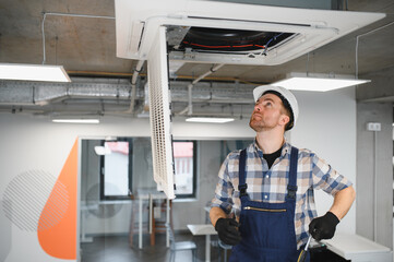 Hvac technician installing air conditioning unit in office building