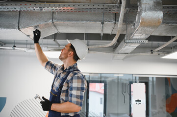 Hvac technician installing ventilation system in building under construction