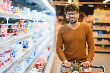 Smiling arab man pushing shopping cart in supermarket