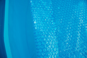 The blue coating of the pool, reflecting sunlight, emphasizes summer recreation and pool maintenance.