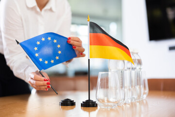 Little flag of Germany on table with bottles of water and flag of European Union put next to it by...