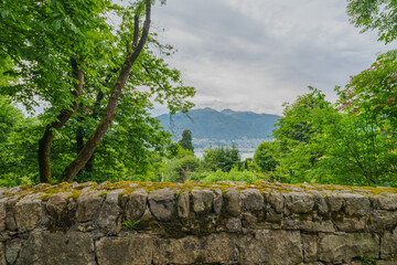 scenic view of a lush green landscape with a stone wall overlooking the picturesque mountains and lake of Switzerland