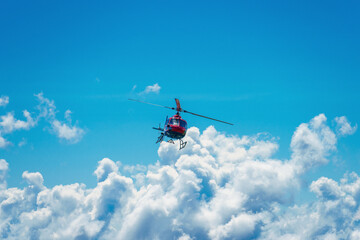 vibrant red helicopter soaring high above the clouds, showcasing the breathtaking beauty of the Swiss Alps under a clear blue sky