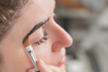 Caucasian woman getting eyebrow tinting procedure. 
