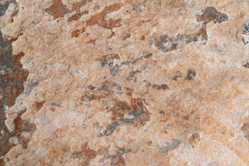 Aged rock background featuring coarse mineral layers, erosion marks, and earthy tones
