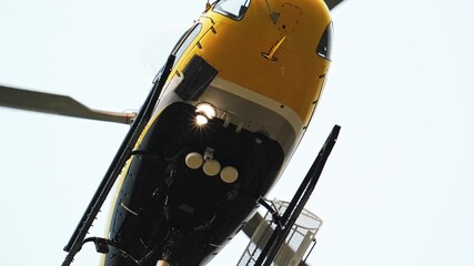 close up Yellow and black firefighting helicopter hovering against a bright sky, preparing for wildfire suppression in spain