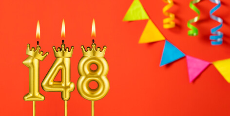 Number 148 birthday candle on an orange background with pennants