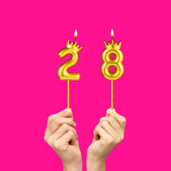 Birthday on a fuchsia background with the number 28 - Hands holding number-shaped candles