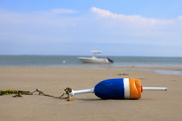 Obraz premium Buoy marks mooring location for boats to tie up. Boat resting on its laurels at low tide.