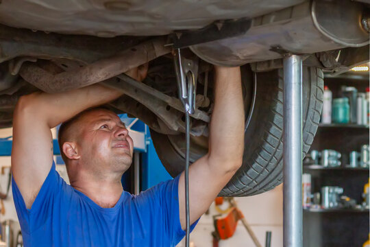 Master replacing of muffler of exhaust system in car workshop. Car exhaust system repair.