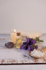 Vertical shot of a spa table composition with essential oil, some lavender flowers, salts, and a towel.