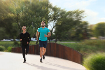 Woman and man in sportswear running outdoors, motion blur effect