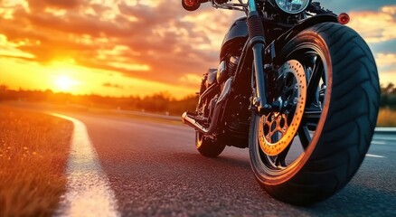 Naklejka premium Close-up view of a motorcycle parked on a road during a vibrant sunset with a dramatic sky and warm golden light