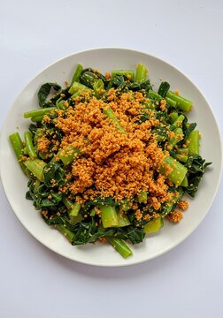 Indonesian urap vegetables with spiced grated coconut topping, neatly plated on a white dish, isolated on white background. Bright natural light, top view.