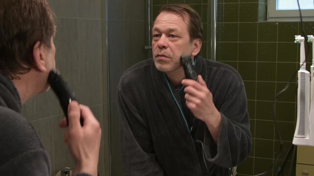 a grown man looks in the mirror and carefully 1