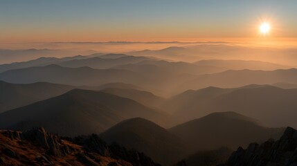 Obraz premium A breathtaking vista of layered mountain ranges bathed in the warm hues of a golden sunrise, showcasing a serene and majestic landscape.