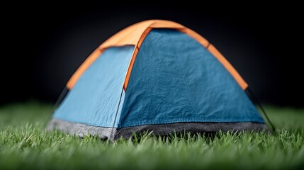 Blue and orange camping tent pitched on green grass with a dark background