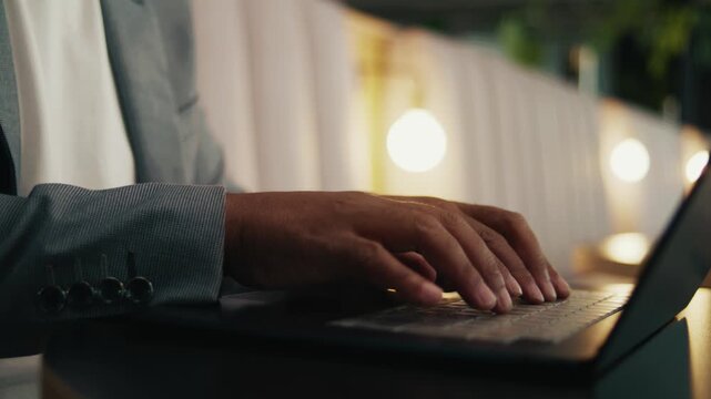 A closeup shot of faceless businessman in suit typing on laptop in office lounge