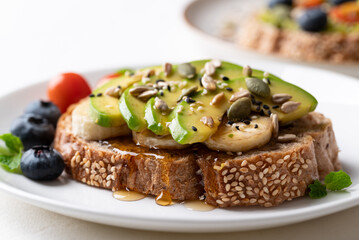 Avocado toast with banana, sunflower seeds, pumpkin seeds, sesame seeds, blueberries, tomatoes and honey, Healthy eating