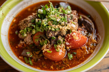 Close up of Khanom Jeen Nam Ngeow (Northern Thai Spicy Noodle Soup) served on table. Spicy Noodle Soup is influenced by Thai-Yai, now this food is an iconic northern Thai food.