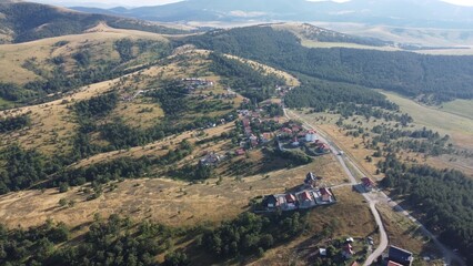Fototapeta premium Aerial view of Zlatibor highlands village with forested hills and scattered houses in summer. g.