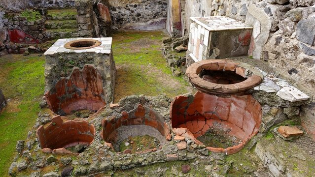 Herculaneum, Italy - 9 January 2025. Fragmented terracotta dolia embedded in counters mark the remains of a Roman street food shop.