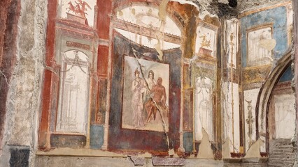 Herculaneum, Italy - 9 January 2025. Fresco with seated mythic trio surrounded by columns and...